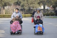 Two elderly people are seen on their wheelchairs at a park in Beijing, on December 11, 2012. China's elderly face increasing uncertainty three decades since the one-child policy took hold, with no real social safety net, the law has left four grandparents and two parents with one caretaker for old age -- and bereaved families with none