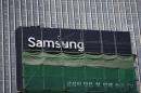 A worker works on a Samsung outdoor advertisement installed atop an office building in central Seoul