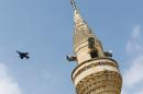 A Turkish Air Force F-16 fighter flies over a minaret after it took off from Incirlik air base in Adana