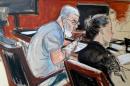 In this courtroom drawing, Mustafa Kamel Mustafa, clasps a pen in his prosthetic hand while sitting next to Mayerlin Ulerio, a paralegal on his defense team, Wednesday, May 7, 2014, during his terrorism trial at federal court in New York. After taking the stand in his own defense, Mustafa calmly denied participating in a December 1998 kidnapping in Yemen; trying to organize a jihad training camp in Bly, Oregon; aiding al-Qaida or sending anyone to Afghanistan to engage in jihad training. (AP Photo/Elizabeth Williams)