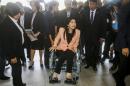 Thailand's Prime Minister Yingluck Shinawatra arrives on a wheelchair at the Royal Police Cadet Academy in Nakorn Pathom province