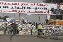 Members of the Muslim Brotherhood and supporters of deposed Egyptian President Mohamed Mursi stand guard in front of sandbags placed at the entrance to their camp near the Tomb of the Unknown Soldier, close to Rabaa Adawiya Square
