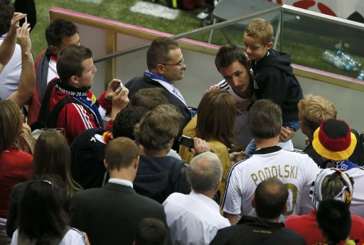 Germany's Klose holds a child as he talks to fans after losing their Euro 2012 semi-final soccer match against Italy at the National Stadium in Warsaw
