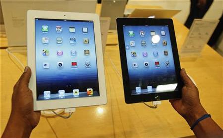 A man inspects the Apple New iPad next to an iPad 2 at an electronics store in Mumbai