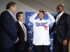 Dodgers' new left-handed pitcher Hyun-Jin Ryu of South Korea wears a cap as he puts on his new jersey while standing with general manager Colletti, owner Magic Johnson, and his agent Boras at a news conference in Los Angeles