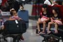 Children sit on the luggage carts as they stranded at the Beijing Capital International Airport after flights are canceled due to the heavy rains in Beijing, China Saturday, July 21, 2012. Heavy downpour flooded roads and caused hundreds of flights to be canceled in the capital. (AP Photo) CHINA OUT