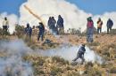 An independent miner returns a tear gas capsule during clashes with riot police during a protest in Panduro