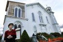 In this May 10, 2012 photo, Suzanne Kelley, chair of the board of trustees, stands below the damaged clock tower of The First Church of Monson Congregational in Monson, Mass., a year after a tornado moved through central Massachusetts and ravaged the town. (AP Photo/Elise Amendola)
