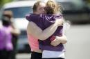 Briannah Wilson, 21, left, and her sister Brittanie Wilson, 19, right, embrace after students arrived at shopping center parking lot in Wood Village, Ore., after a shooting at Reynolds High School Tuesday, June 10, 2014, in nearby Troutdale. A gunman killed a student at the high school east of Portland Tuesday and the shooter is also dead, police said. (AP Photo/Troy Wayrynen)