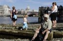 People walk by the River Thames on the South Bank during a warm day in London