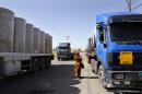 In this picture taken on Sunday, April 26, 2015, a woman walks through lines of trailer trucks sitting idle at the Jaber border crossing between Jordan and Syria north of Mafraq. Jordan's overland trade has largely been paralyzed by recent border attacks from insurgents in neighboring Syria and Iraq. The violence has forced the closure of the only Syrian-Jordan trade crossing and further disrupted already sharply diminished cargo shipments between Jordan and Iraq. (AP Photo/Raad Adayleh)