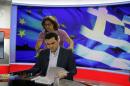 Greece's Prime Minister Alexis Tsipras takes a look at his notes as a technician prepares him before a TV interview at the State Television (ERT) in Athens, Monday, June 29, 2015. Anxious pensioners swarmed closed bank branches Monday and long lines snaked at ATMs as Greeks endured the first day of serious controls on their daily economic lives ahead of a July 5 referendum that could determine whether the country has to ditch the euro currency and return to the drachma. (AP Photo/Thanassis Stavrakis)