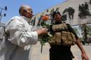 An Iraqi man gives a rose to a member of the security forces on August 3, 2016 in Baghdad's Tahrir Square, a month after the deadliest single bombing ever to strike the capital