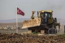 A digger, belonging to Turkish army, is parked next to a Turkish flag at the new site of the Suleyman Shah tomb in the northern Syrian village of Esmesi, Aleppo province