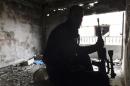 A Free Syrian Fighter holds his weapon inside a damaged building in the besieged area of Homs