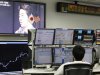 An employee of a foreign exchange trading company looks at monitors as a television set shows Japan's incoming Prime Minister and the leader of Liberal Democratic Party (LDP) Shinzo Abe speaking in Tokyo