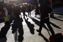 People walk in the late afternoon sun through Times Square in New York