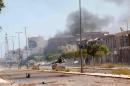 Fighters ride a pickup truck as smoke rises during a battle with Islamic State fighters in neighborhood Number Two in Sirte
