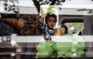 A migrant child looks through a bus window while waiting&nbsp;&hellip;