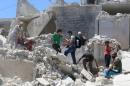 People walk on the rubble of a site hit by a barrel bomb in the rebel held area of Old Aleppo