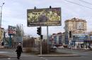 A woman walks under a billboard featuring a picture of the leader of the self-proclaimed Donetsk People's Republic Alexander Zakharchenko (C) and reading: "we are grateful to the defenders of the fatherland" in Donetsk, Ukraine, March 18, 2015