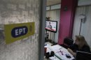 An employee watches a speech by Greece's PM Samaras on a television screen, inside Greek state television ERT headquarters in Athens