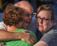 Tom Sullivan, center, embraces family members outside Gateway High School where he has been searching franticly for his son Alex Sullivan who celebrated his 27th birthday by going to see "The Dark Knight Rises," movie where a gunman opened fire Friday, July 20, 2012, in Aurora, Colo. (AP Photo/Barry Gutierrez)