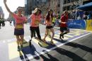 Double amputee Celeste Corcoran, center, a victim of last year's bombings, reaches the finish line of the 118th Boston Marathon, Monday, April 21, 2014, in Boston, with the aid her sister Carmen Acabbo, left, and daughter Sydney, right, who was also wounded last year. (AP Photo/Elise Amendola)