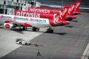 A ground crew man walks past a fleet of AirAsia's passenger jets on the tarmac of the new low cost terminal KLIA2 in Sepang, Malaysia, Friday, May 9, 2014. AirAsia on Friday began its full operations from KLIA2. (AP Photo/Joshua Paul)