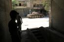 Opposition fighters take cover as a tank belonging to their forces is seen in a street of the Syrian city of Aleppo on April 27, 2014