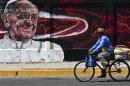 A man rides a bicycle past a poster welcoming Pope Francis to Ecatepec, Mexico on February 5, 2016
