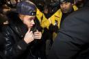 Canadian musician Justin Bieber is swarmed by media and police officers as he turns himself into city police for an expected assault charge, in Toronto, on Wednesday, Jan. 29, 2014. A police official said the charge has to do with an alleged assault on a limo driver in December. (AP Photo/The Canadian Press, Nathan Denette)