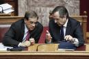 Greek Prime minister Antonis Samaras, right, chats with Greece's Finance Minister Gikas Hardouvelis during a debate on a confidence vote demanded by the conservative-led governing coalition half-way through its four-year mandate, in Athens on Friday, Oct. 10, 2014. Prime Minister Antonis Samaras' government is expected to win the vote, but it faces possible early elections soon as it will need opposition support to elect Greece's new president in March. (AP Photo/Petros Giannakouris)