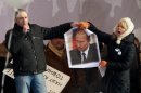 In this Saturday, Feb. 4, 2012 file photo, Russian opposition leader Sergei Udaltsov, left, with environmental activist Yevgenia Chirikova tears a picture of then Russian Prime Minister Vladimir Putin to pieces as he stands on a stage addressing a massive protest against Putin's rule in Moscow, Russia. Putin has taken a harder line against the opposition since returning to the presidency a month ago. He seems to be betting that by threatening demonstrators with prison time and onerous fines he can quash the street protests that have posed an unprecedented challenge to his 12-year rule. (AP Photo/Ivan Sekretarev)