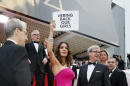 Actress Salma Hayek holds up a sign reading "bring back our girls", part of a campaign calling for the release of nearly 300 abducted Nigerian schoolgirls being held by Nigerian Islamic extremist group Boko Haram, as she arrives for the screening of Saint-Laurent at the 67th international film festival, Cannes, southern France, Saturday, May 17, 2014.(AP Photo/Alastair Grant)