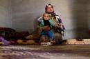 In this picture taken, Wednesday, May 6, 2015, Syrian refugee Fatmeh Ahmed, 20, holds her 10-month-old son, Hassan, in their shack on a peach farm near the northern Jordanian community of Salhiyeh. Ahmed, and her husband live on $9-a-day jobs on the farm, after they lost $100 a month in food vouchers due to cuts by the cash-strapped World Food Program. (AP Photo/Raad Adayleh)
