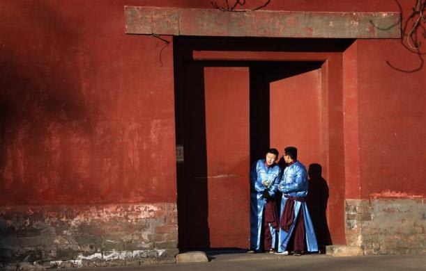 Para aktor mengenakan kostum tradisional mengintip dari pintu kecil saat bersiap-siap menghadiri upacara kuno Dinasti Qing di Kuil Bumi,  Beijing, 22 Januari 2012.