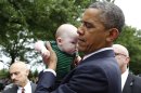 President Barack Obama picks up 4-month-old Parker Cornell of Hubert, N.C., while visiting Section 60 on Memorial Day at Arlington National Cemetery in Arlington, Va., Monday, May 27, 2013. (AP Photo/Molly Riley)