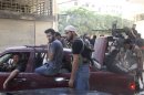 Free Syrian Army fighters carry their weapons and sit in cars and pick-up trucks near the frontline in the refugee camp of Yarmouk, near Damascus