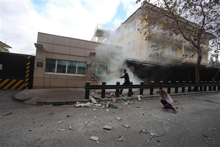 A security officer runs after an explosion at the entrance of the U.S. embassy in Ankara February 1, 2013. A suicide bomber killed a Turkish security guard (not in picture) at the U.S. embassy in Ankara on Friday, blowing the door off a side entrance and sending smoke and debris flying into the street. REUTERS/Yavuz Ozden/Milliyet Daily Newspaper