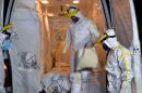 An ambulance is readied by technicians wearing bio-hazard protective clothing, to transport a Guinean patient suspected of having Ebola, in Cascavel on October 10, 2014