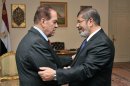 In this photo released by Middle East News Agency, the Egyptian official news agency, caretaker Prime Minister Kamal el-Ganzouri, left, shakes hands with newly elected President Mohammed Morsi in Cairo, Egypt, Monday, June 25, 2012. Morsi met with the military-backed Prime Minister el-Ganzouri, who resigned Monday and was asked to head a caretaker government until Morsi nominates a new one. (AP Photo/Middle East News Agency, HO)