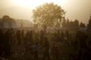 People gather in a field as the sun sets at a makeshift camp for refugees and migrants at the Greek-Macedonian border near the village of Idomeni, Greece