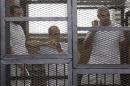 Al Jazeera journalists Baher Mohamed, Peter Greste and Mohammed Fahmy stand behind bars at a court in Cairo