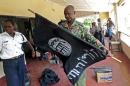 A Kenyan police officer folds up a flag inscribed with the logo of the Islamic state (IS) following a raid on two mosques in the coastal city of Mombasa, on November 17, 2014