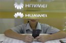 A sales assistant looks at her mobile phone as she waits for customers behind a counter at a Huawei booth in Wuhan