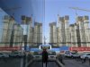 A construction site of a residential compound is reflected on the glass facades of a office building in Taiyuan