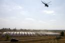 A helicopter flies over trucks from a Russian humanitarian convoy parked on a field outside the town of Kamensk-Shakhtinsky in the Rostov region, some 30kms from the Russian-Ukrainian border on August 14, 2014