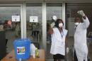 Health workers wearing protective masks and gloves gesture as they talk at the Felix Houphouet Boigny international airport in Abidjan