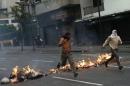 Opposition students run from police and past burning trash as they protest against President Nicolas Maduro's government in Caracas